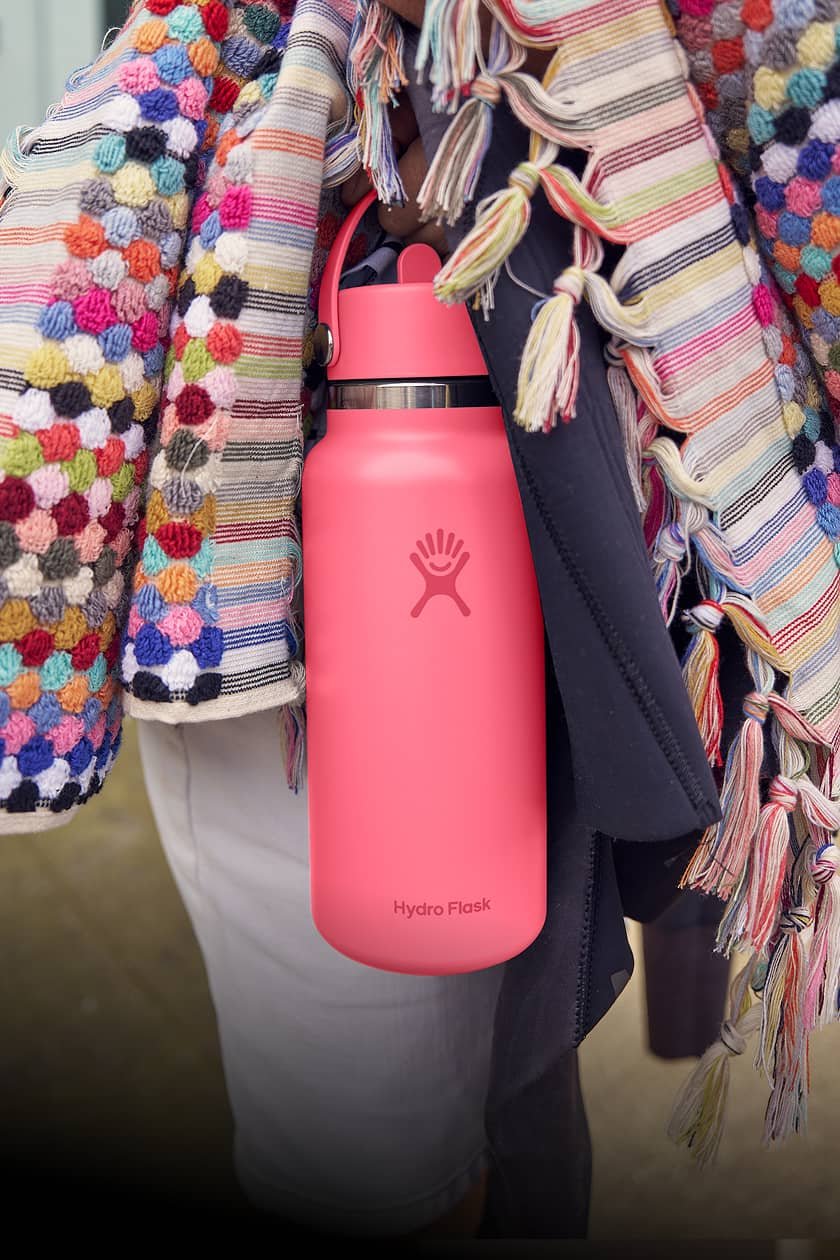 new popstar pink hydro flask bottle in hand with colorful blanket
